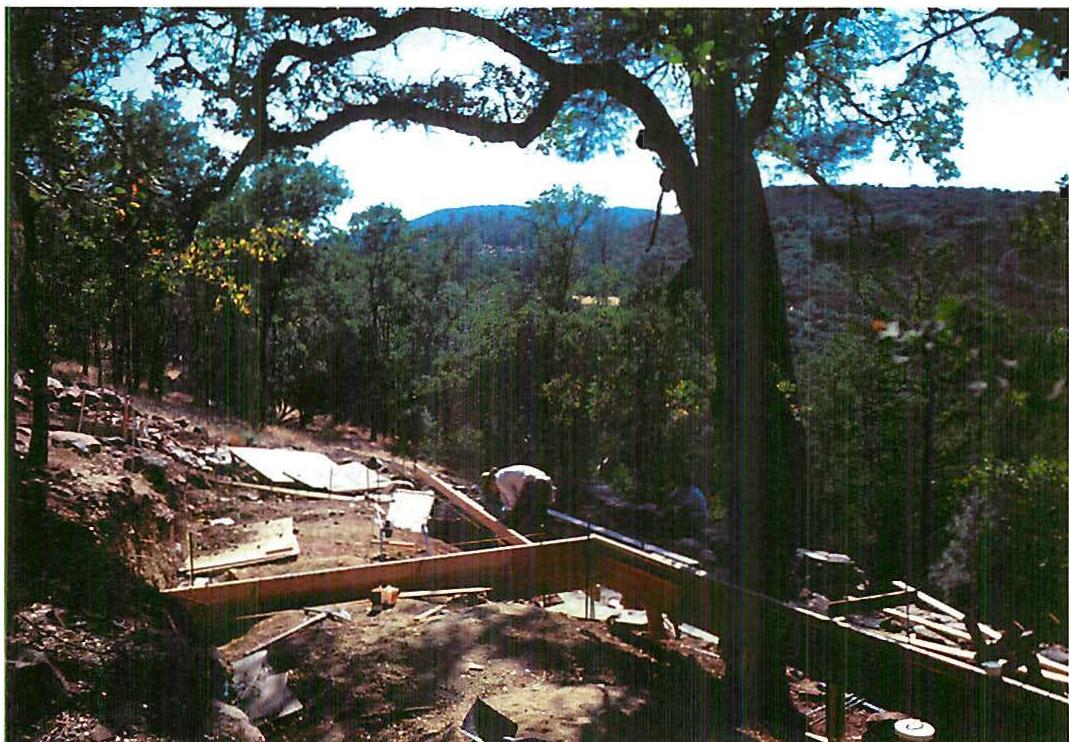 Berryessa house, 1986–87. The site at Berryessa during construction, when both position and design and slab-forming are going on together. Slabs are being placed, carefully, in such a way as to preserve the structure of the land and of the white oak trees. Christopher Alexander with Artemis Anninou and Gary Black.
